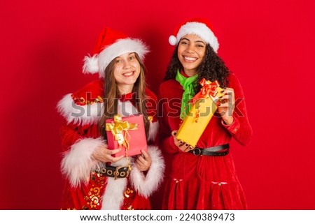 two brazilian friends, dressed in christmas clothes, santa claus, giving christmas presents to camera.