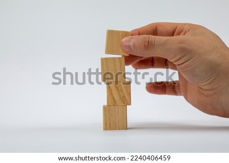 Hand cutting and stacking blank wooden cubes on table with copy space for input wording and infographic icon.
