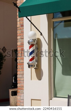 View of an old style barber's pole or sign on the outside of a barber shop.
