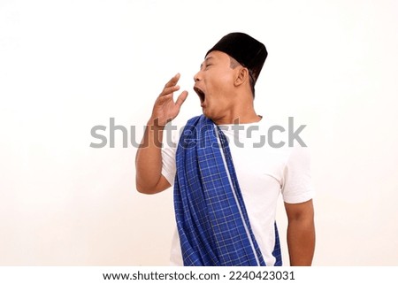 Portrait of funny Asian man yawning and showing a sleepy gesture. Isolated on white background