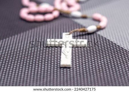 A small cross attached to a necklace lies on the table