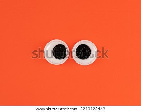 Cute googly eyes funny Isolated on bright orange background copy space logo