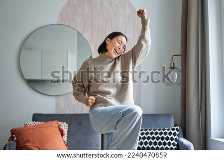 Portrait of happy asian woman dancing, rejoicing and triumphing, feeling upbeat at home. Copy space