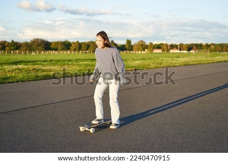 Hobbies and lifestyle. Young woman riding skateboard. Skater girl enjoying cruise on longboard on sunny day outdoors.