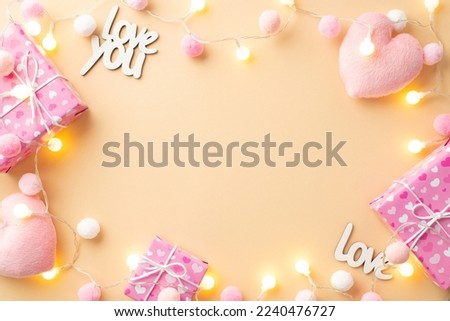 Valentine's Day concept. Top view photo of gift boxes fluffy heart shaped toys inscription love you light bulb garland and soft pompons on isolated pastel beige background with copyspace in the middle