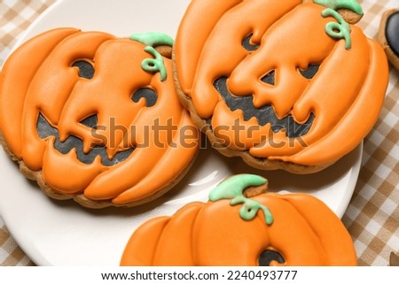 Plate with Halloween pumpkin cookies on checkered napkin, closeup