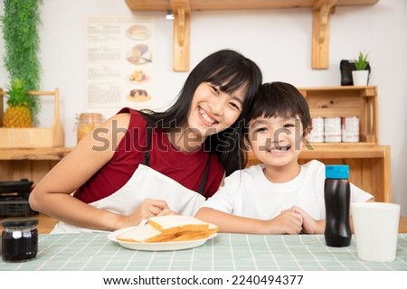Happy Asian couple family smiling at camera during breakfast in kitchen. Portrait of young mother and her son having breakfast together