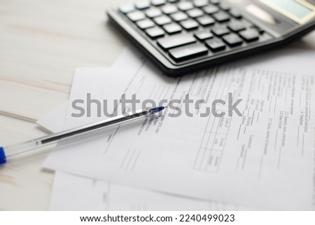 Photo of a pen lying on documents and a calculator in the background
