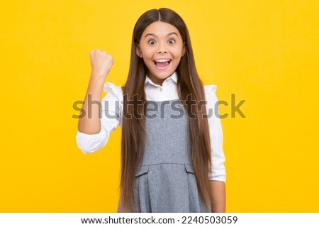 Excited face, cheerful emotions of teenager girl. Teenager child overjoyed successful do winner gesture clench fist say yes isolated on yellow background studio.