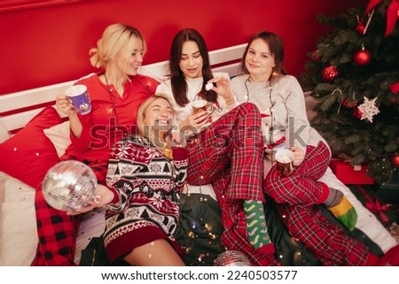 Girls pajamas party near Christmas tree with drinks and sparkles. Best happy friends hanging out, having fun, laughing