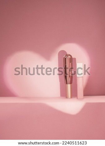 Two cosmetics tubes standing on a pink background .Shadow in the form of a heart on the background.Beauty,Cosmetics Gift on Valentines day
