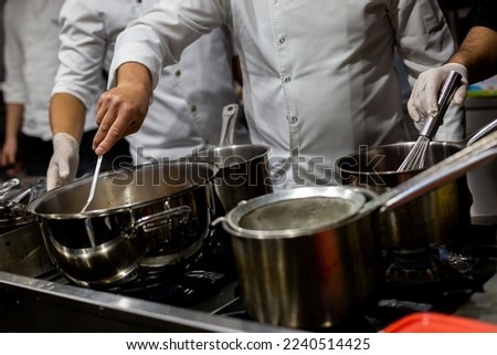 A cook stirring pots in the kitchen. Big pots in the kitchen. SELECTİVE FOCUS
