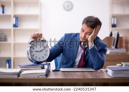 Young male employee in time management concept Royalty-Free Stock Photo #2240531347