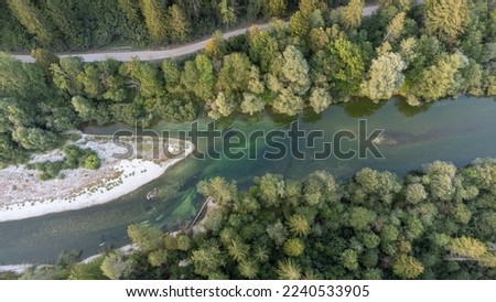 Overhead shot of river Sava Bohinjka near Bled, with a gravel road running parallel and woods on either side. Gravel dune in the middle of the river Royalty-Free Stock Photo #2240533905