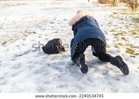 woman slips and falls down on snowy road.