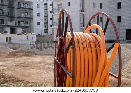 Communications development, Large coils reel of orange PVC pipe tube plastic on construction site in Israel. protect cables  Royalty-Free Stock Photo #2240559733