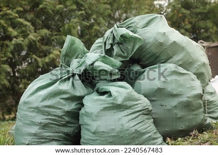 Pile of green plastic free ecological trash bags on dump outdoors. Segregation, sorting and recycling of garbage. Volunteer action, clean the planet, environmental conservation, air pollution Royalty-Free Stock Photo #2240567483