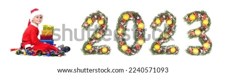 Boy Santa Claus is holding a christmas gift and 2023 number made by christmas tree branches isolated on white background