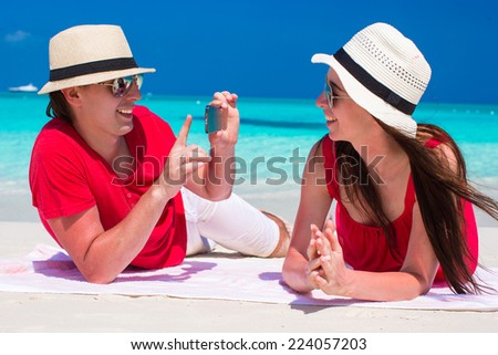 Young boy takes a picture of girl on the beach