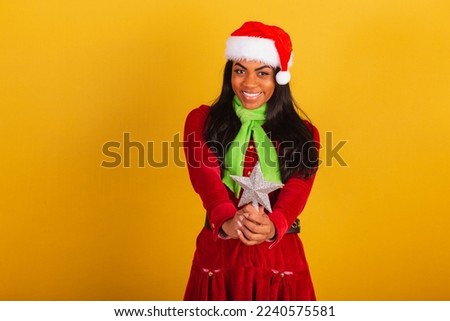 Beautiful black Brazilian woman, dressed in christmas clothes, santa claus, holding christmas star.
