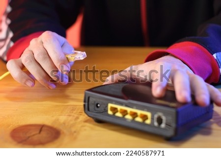 connecting internet cable to old adsl modem on table by background person
