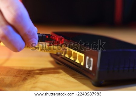 person in background inserting internet cable into old adsl modem