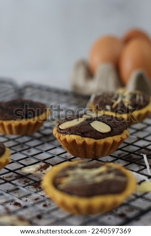 Small chocolate pie with almonds topping served on a cake rack, tastes sweet and savory. Food concept photo.
