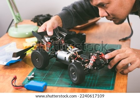 The man working on radio controlled buggy car. RC car assembly scene. Royalty-Free Stock Photo #2240617109