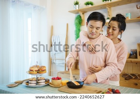 Happy young couple cooks a breakfast together in kitchen, romantic Asian young couple cooking a breakfast in the morning.