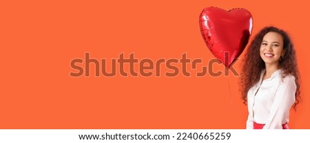 Pretty African-American woman holding heart-shaped balloon on orange background with space for text. Valentine's Day celebration