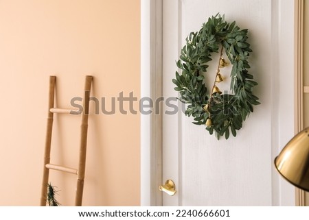 Christmas wreath with bells on white door in living room, closeup