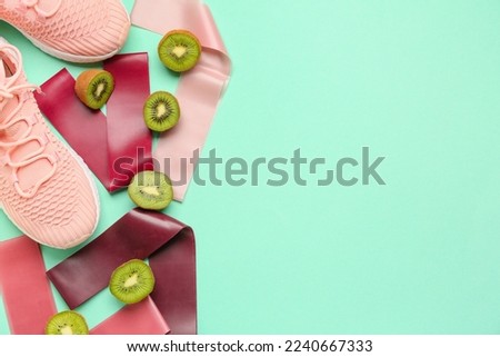 Resistance bands, shoes and kiwi on color background