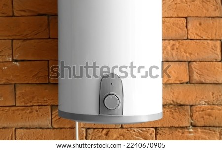 Modern electric boiler on brick wall, closeup Royalty-Free Stock Photo #2240670905