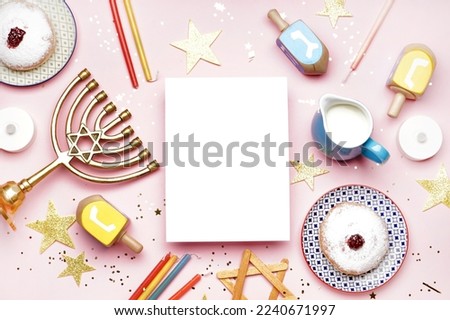 Blank card with menorah, dreidels, treats and stars for Hannukah celebration on pink background