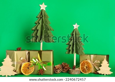 Composition with felt Christmas trees, gifts and decorations on green background