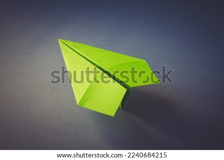 Green paper plane origami isolated on a blank grey background