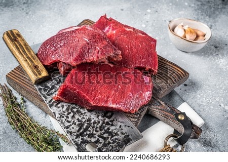Raw Venison dear meat on butcher cutting board, game meat. Gray background. Top view. Royalty-Free Stock Photo #2240686293
