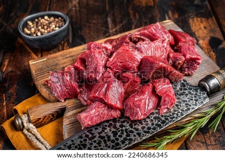 Sliced Raw venison dear meat for a stew, game meat on butcher cutting board. Wooden background. Top view. Royalty-Free Stock Photo #2240686345