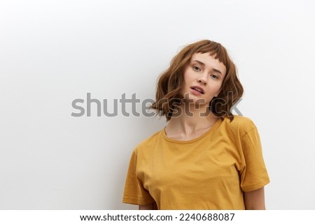 a sweet, beautiful, romantic woman in a yellow T-shirt poses on a white background, smiling pleasantly looking at the camera. Horizontal photo with an empty space for inserting an advertising layout