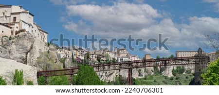 Horizontal panorama of the city of Cuenca in Spain from the Huecar river with the San Pablo bridge in front and blue sky with clouds in the background