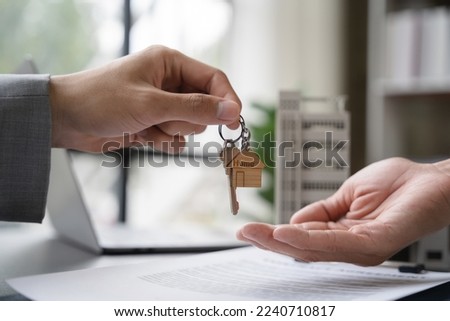 home loan officer gives the house keys to the client after signing a real estate contract with an approved mortgage application regarding the offer of mortgage loans and home insurance. Royalty-Free Stock Photo #2240710817