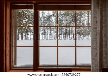 view in winter through a wooden window with trees in the background