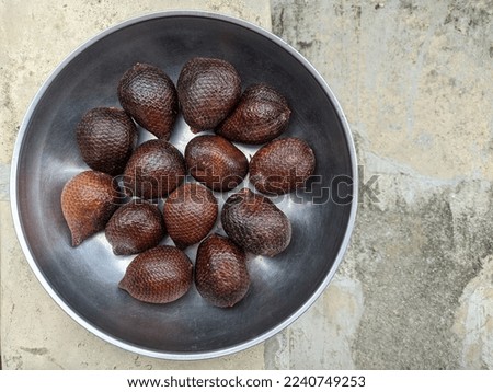 photo of tropical fruit salak or snakefruit on a container