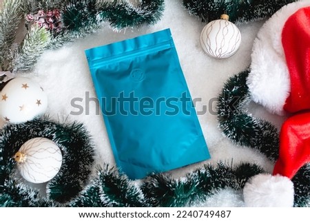 Blank coffee packaging on the background of the Christmas tree, Santas hat, and artificial snow, Christmas balls and tinsel, coffee packaging mockup with empty space to display your branding design