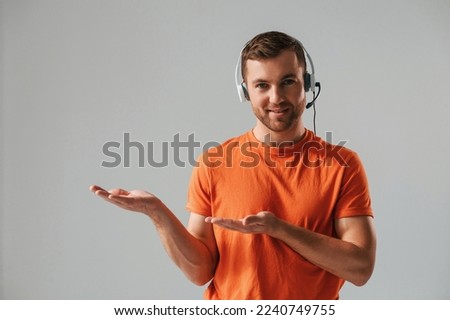 Conception of call center. In headset. Handsome man is in the studio against white background.
