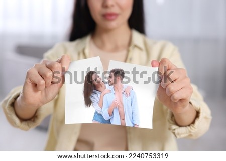 Woman ripping photo at home, focus on picture. Divorce concept