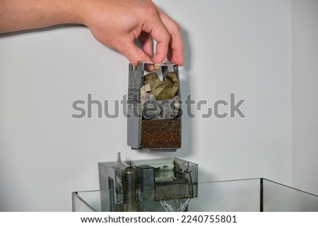 Close up of a hand disassembling a fish tank waterfall filter to clean it. Aquarium maintenance. Royalty-Free Stock Photo #2240755801