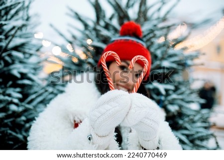 Cheerful young woman laughs and holds New Year's candy lollipops in her hands, Christmas fair, winter. Lifestyle concept.