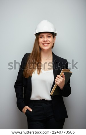 Woman in black business suit wearing safety helmet holding book. engeneer isolated portrait.