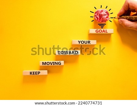 Keep moving toward your goal symbol. Wooden blocks with words Keep moving toward your goal. Beautiful yellow background, copy space. Businessman hand, light bulb. Business, your goal concept.